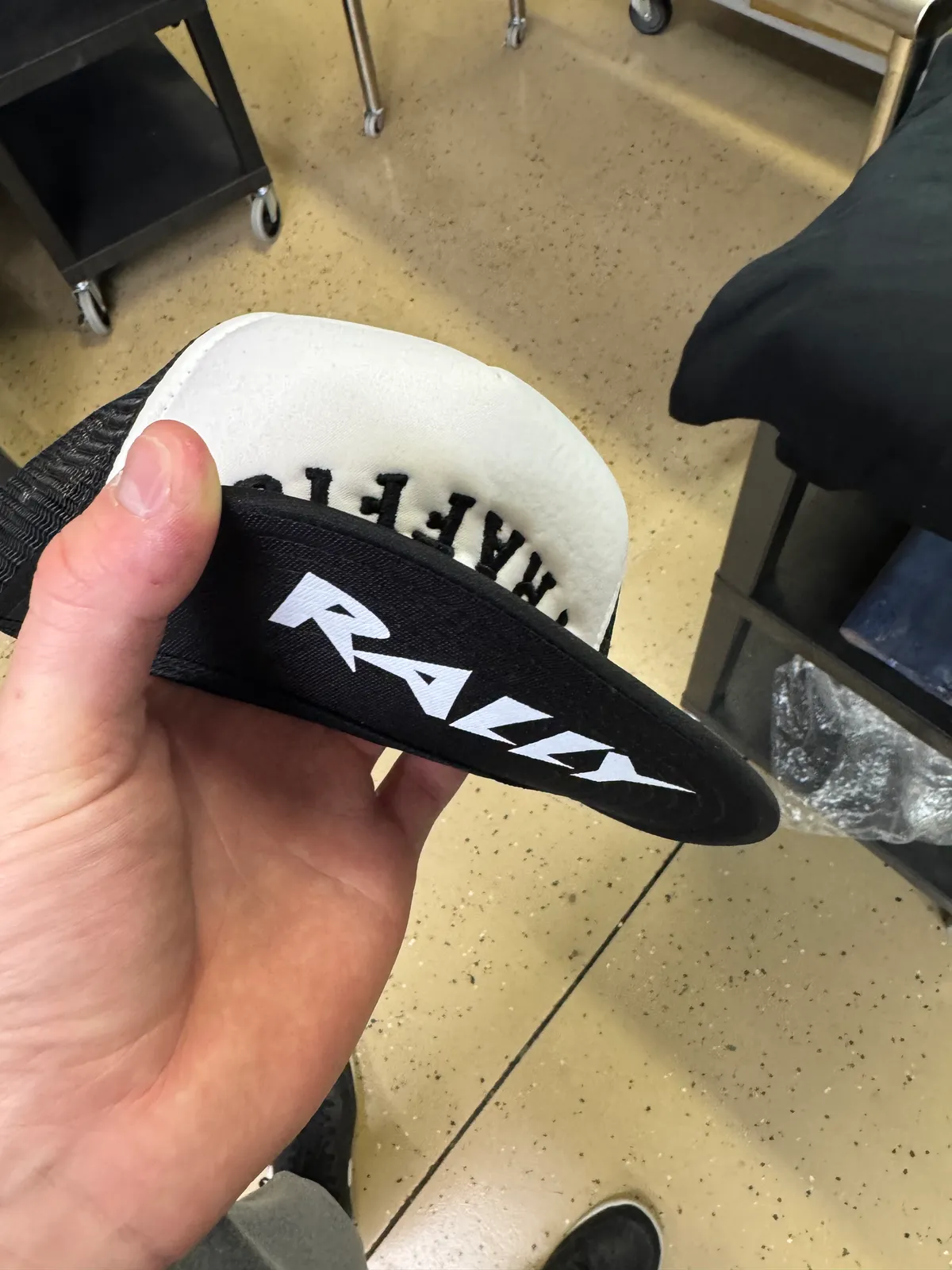 Black and white trucker cap with RALLY printed in white under the brim