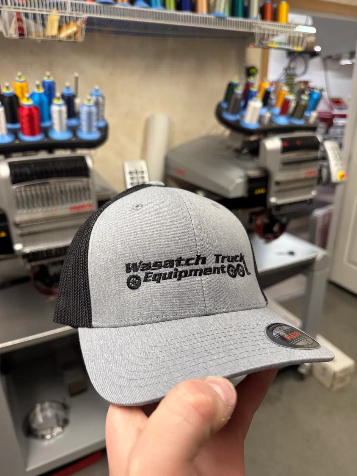 Gray and black trucker cap with a clean black embroidered Wasatch Truck Equipment logo